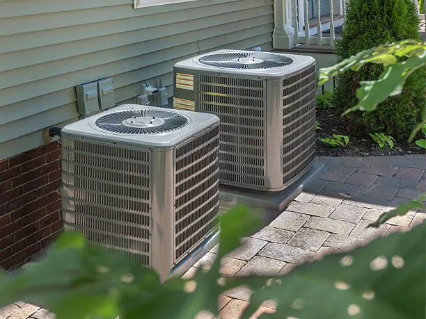 Two outdoor AC units beside a home