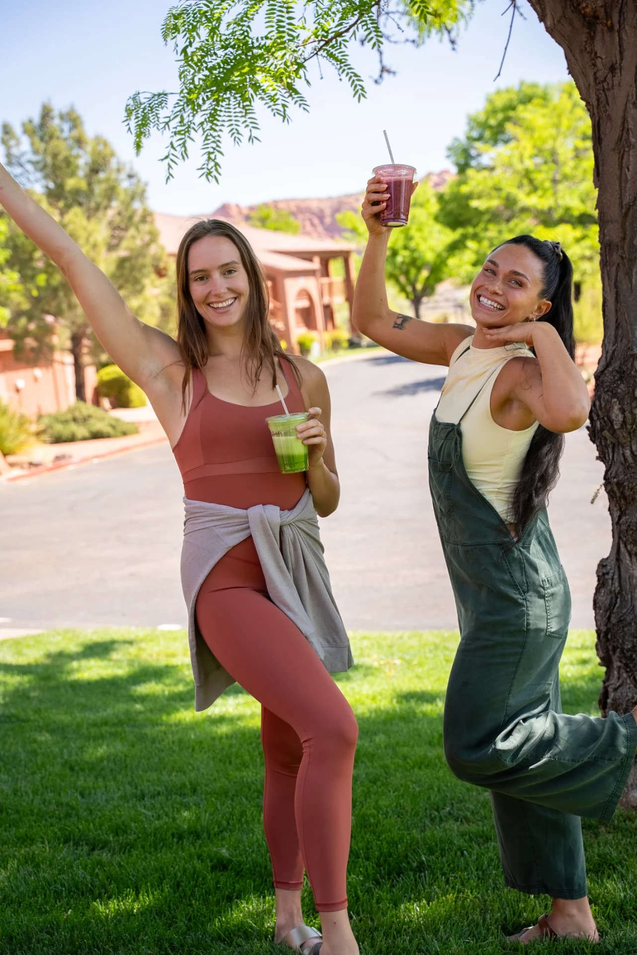 Two friends raising smoothies with red rock cliffs behind