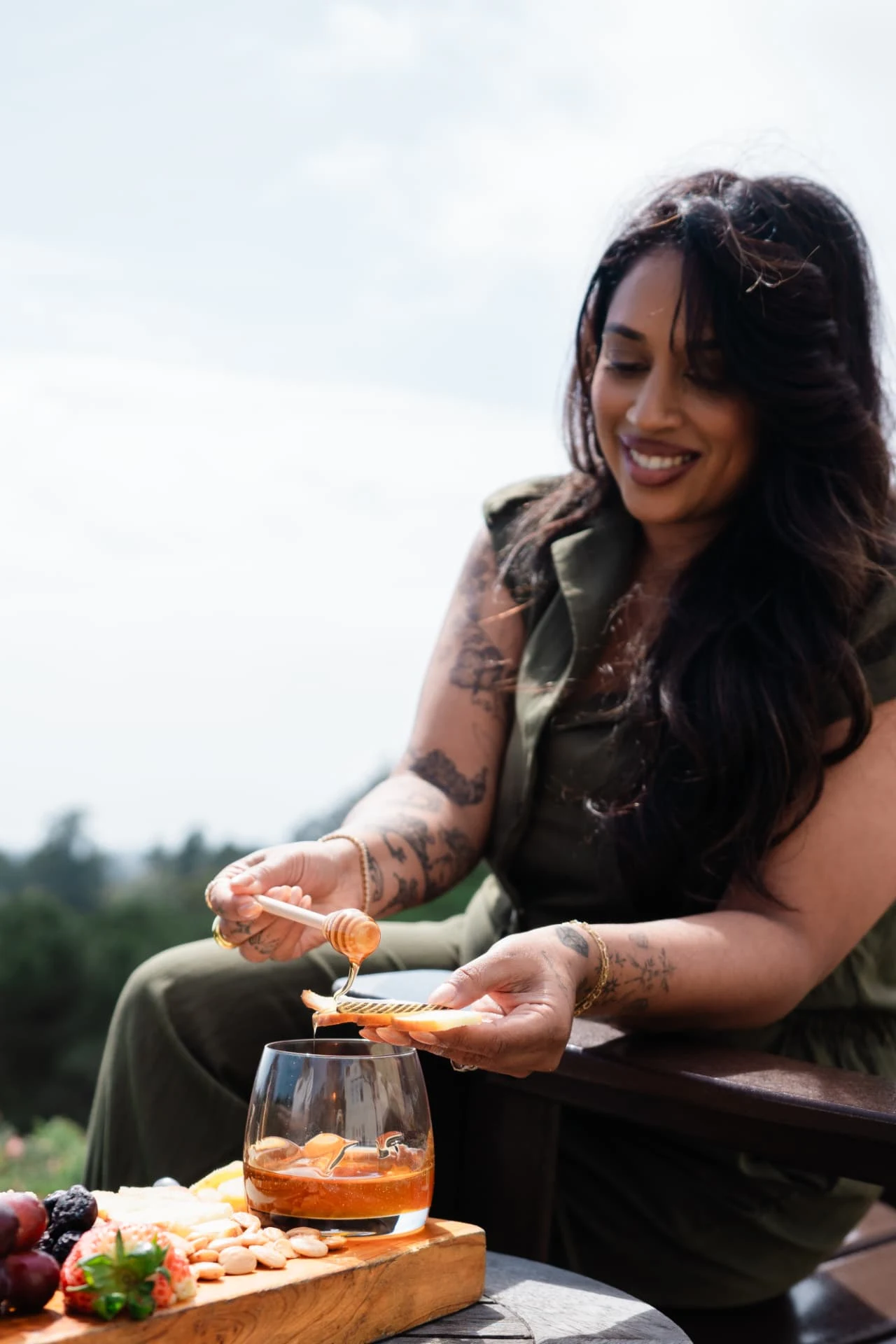 Guest drizzling honey over a cheese board on an outdoor terrace