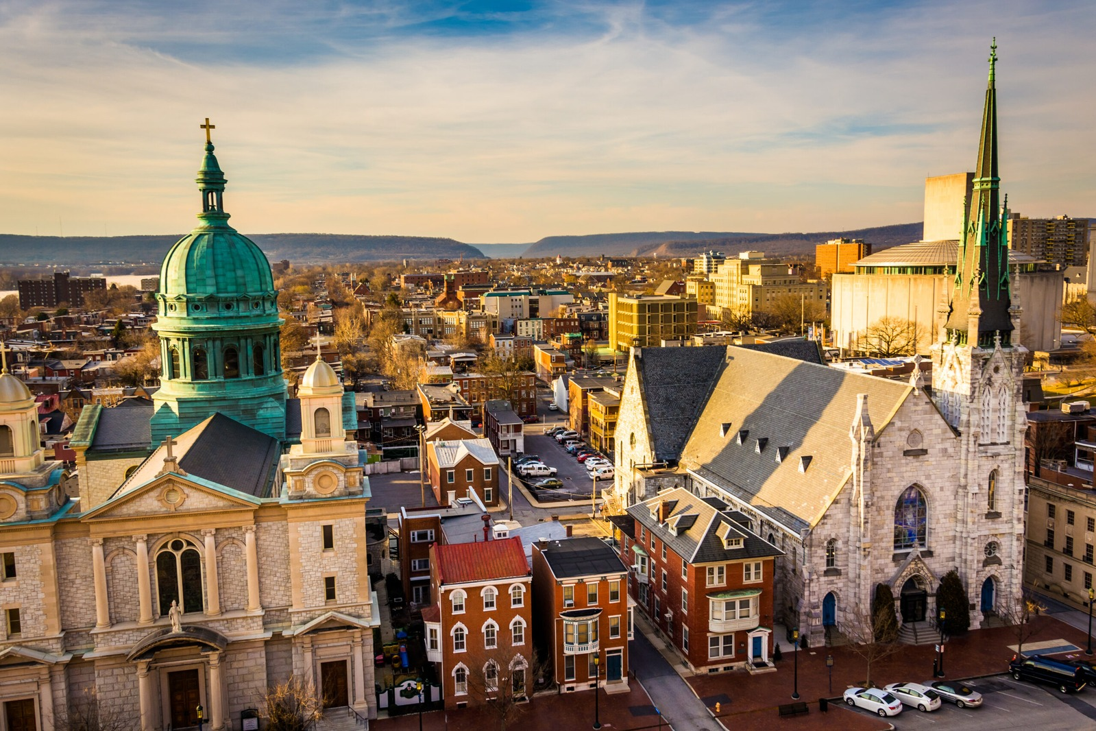Downtown Harrisburg rooftops, church spires and a green dome at golden hour